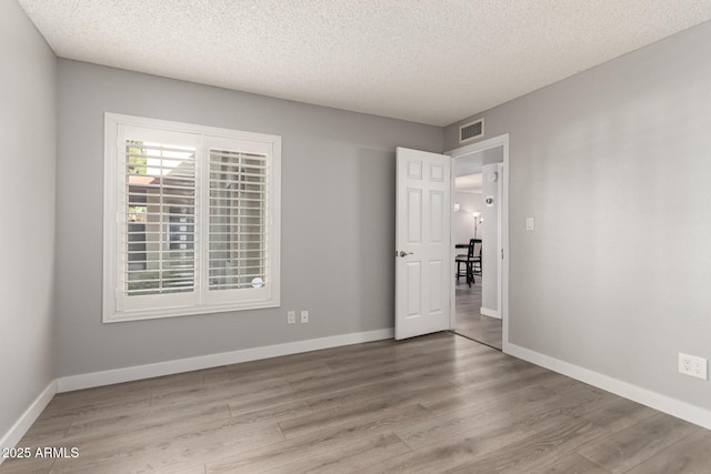 empty room with a textured ceiling and light wood-type flooring