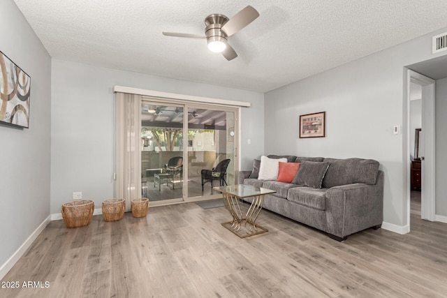 living room featuring a textured ceiling, ceiling fan, and light hardwood / wood-style floors