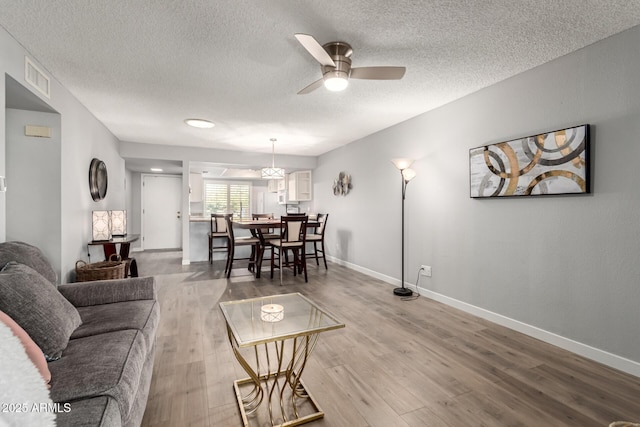 living room with a textured ceiling, ceiling fan, and hardwood / wood-style flooring