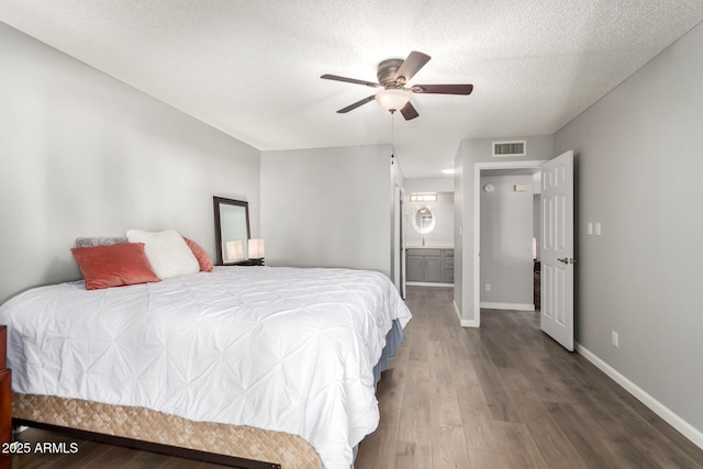 bedroom with ensuite bath, a textured ceiling, ceiling fan, and wood-type flooring