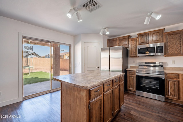 kitchen featuring visible vents, dark wood-style floors, a kitchen island, appliances with stainless steel finishes, and light countertops