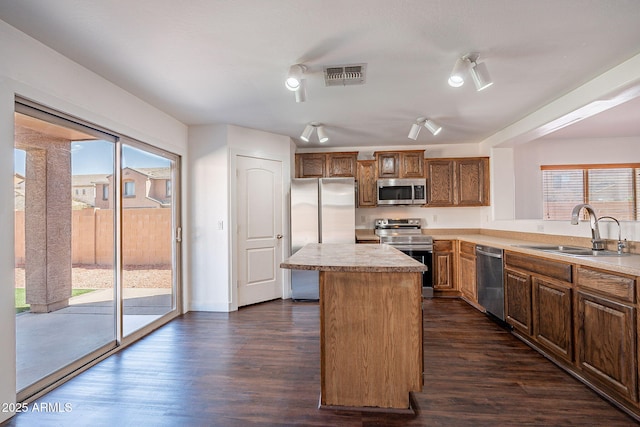 kitchen featuring stainless steel appliances, dark wood-style flooring, a sink, visible vents, and a center island