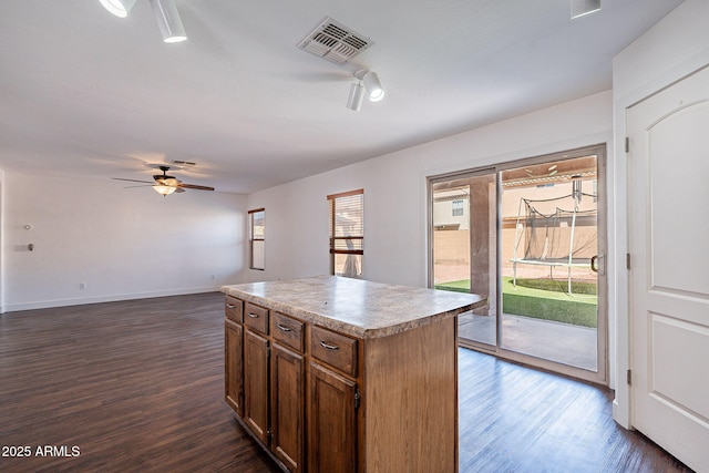 kitchen featuring dark wood-type flooring, visible vents, a kitchen island, and a ceiling fan