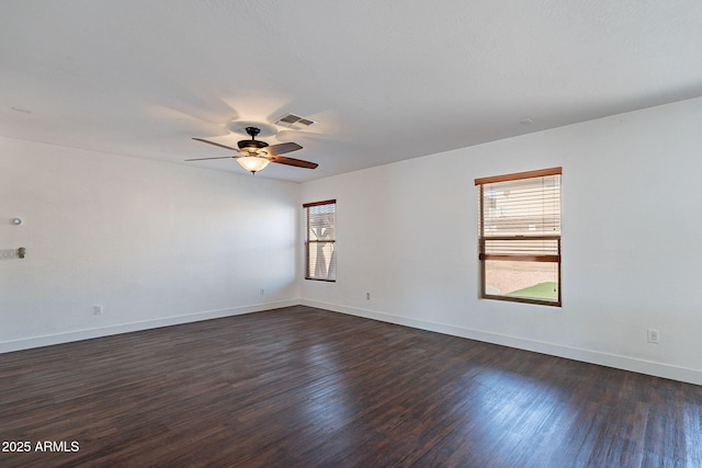 spare room with a ceiling fan, visible vents, dark wood finished floors, and baseboards