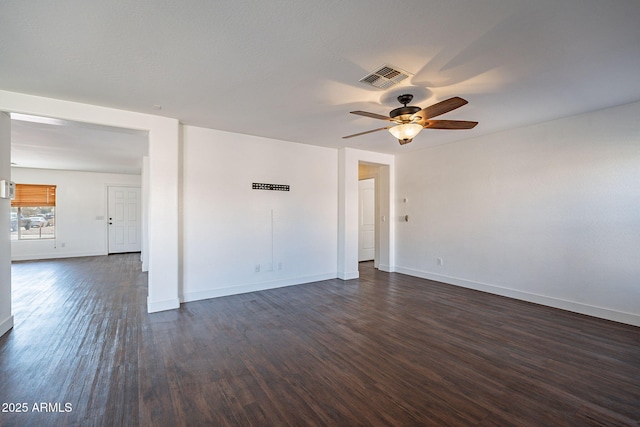 unfurnished room with a ceiling fan, baseboards, visible vents, and dark wood-type flooring