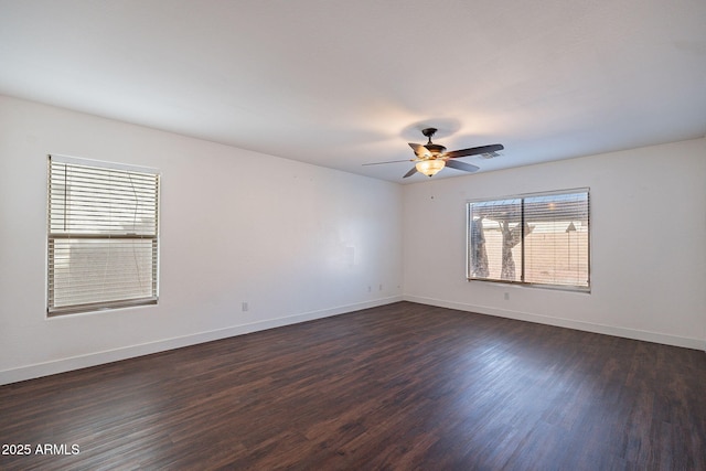 spare room featuring a ceiling fan, visible vents, dark wood finished floors, and baseboards