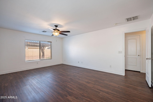 spare room featuring dark wood-style floors, visible vents, and baseboards