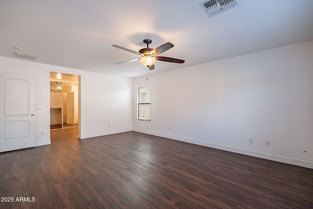 spare room with dark wood-style floors, baseboards, visible vents, and a ceiling fan