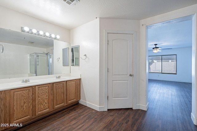 bathroom with a stall shower, visible vents, a sink, and wood finished floors