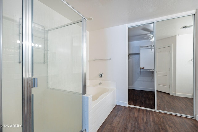 bathroom featuring a garden tub, wood finished floors, a shower stall, and visible vents