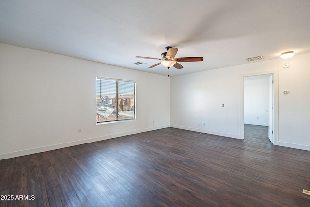 empty room with dark wood-style floors, baseboards, visible vents, and ceiling fan