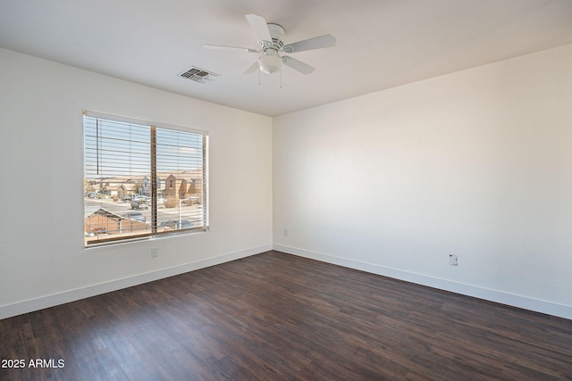 spare room with dark wood-type flooring, visible vents, ceiling fan, and baseboards