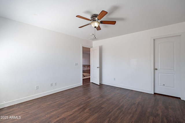 empty room featuring dark wood-type flooring, a ceiling fan, and baseboards