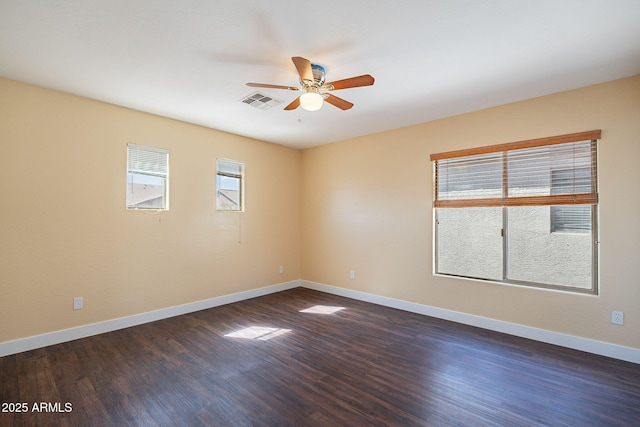 empty room with dark wood-type flooring, visible vents, baseboards, and a ceiling fan