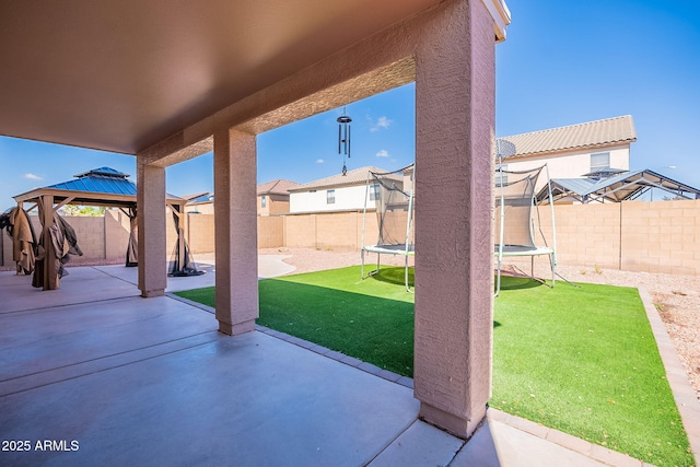 view of patio featuring a gazebo, a trampoline, a fenced backyard, and a residential view