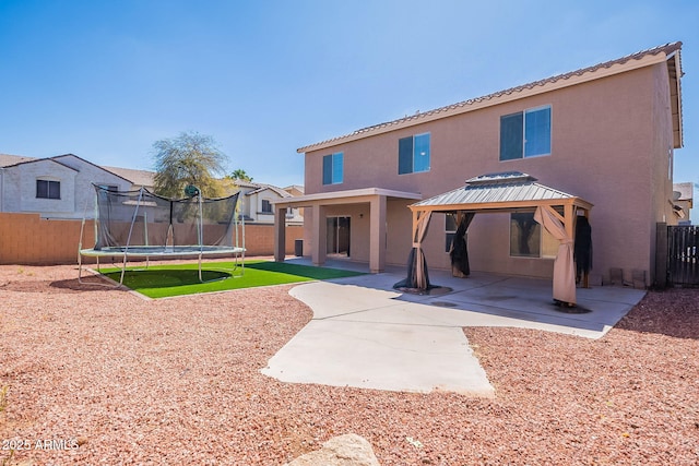 back of property with a patio, a trampoline, fence, a gazebo, and stucco siding