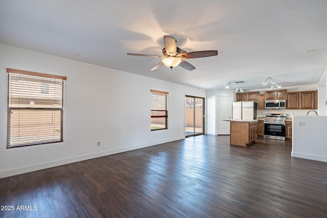 unfurnished living room featuring a ceiling fan, baseboards, and dark wood-type flooring