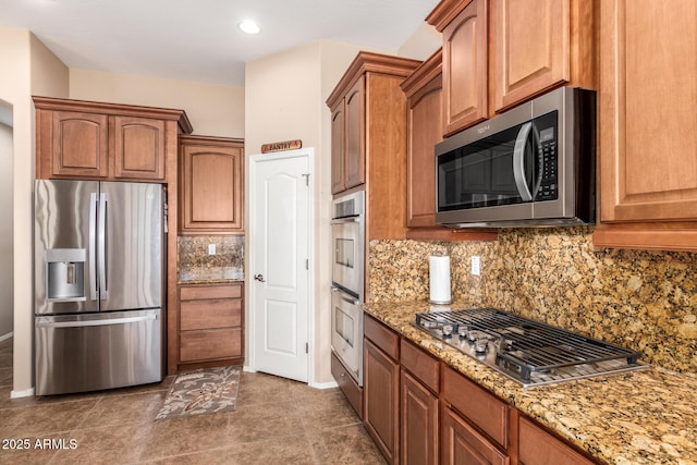 kitchen featuring stainless steel appliances, dark tile patterned floors, tasteful backsplash, and light stone counters