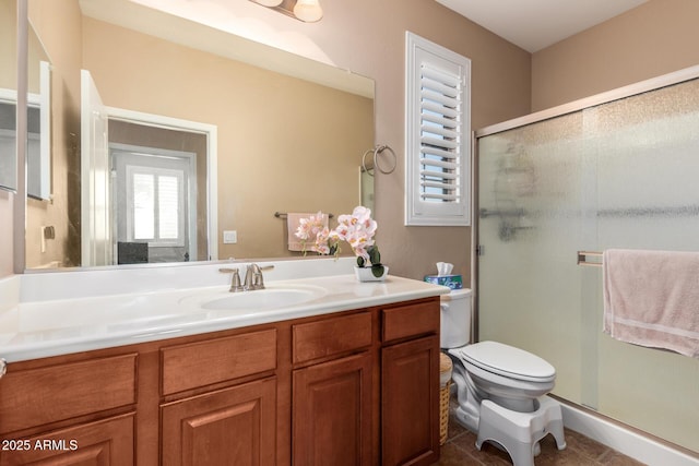 bathroom featuring a shower with door, vanity, and toilet