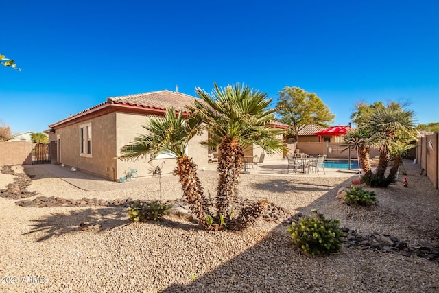 rear view of house featuring a fenced in pool and a patio