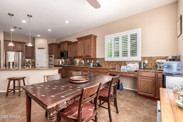 kitchen featuring stainless steel appliances, hanging light fixtures, ceiling fan, light stone counters, and tasteful backsplash