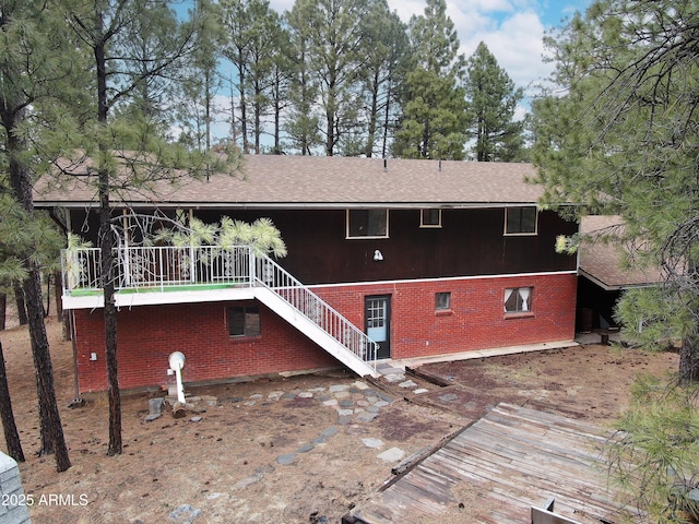 rear view of property with brick siding and stairway