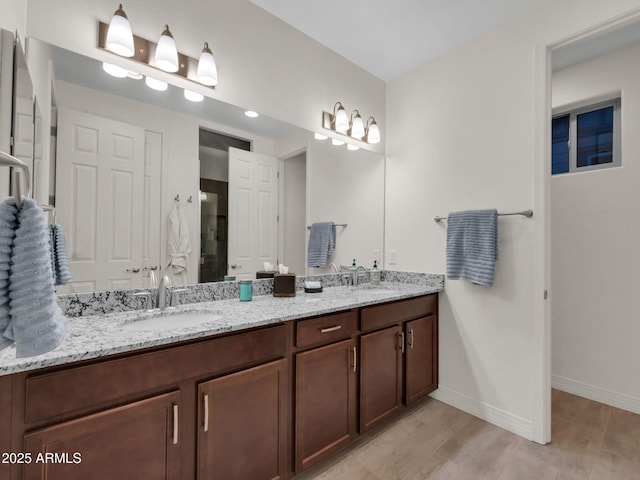 2882 W Presidio Dr, Flagstaff, AZ 86001 - bathroom featuring double vanity, baseboards, a sink, and wood finished floors