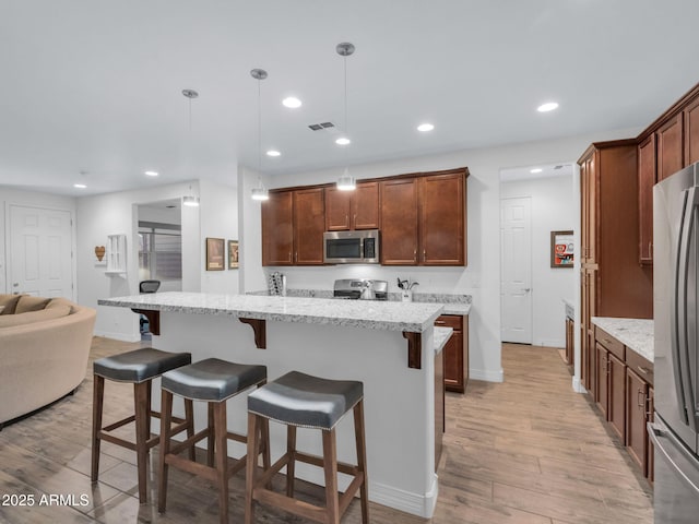 2882 W Presidio Dr, Flagstaff, AZ 86001 - kitchen featuring stainless steel appliances, a center island, decorative light fixtures, and light stone countertops