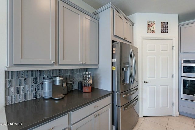 kitchen with stainless steel appliances, gray cabinetry, backsplash, and light tile patterned floors