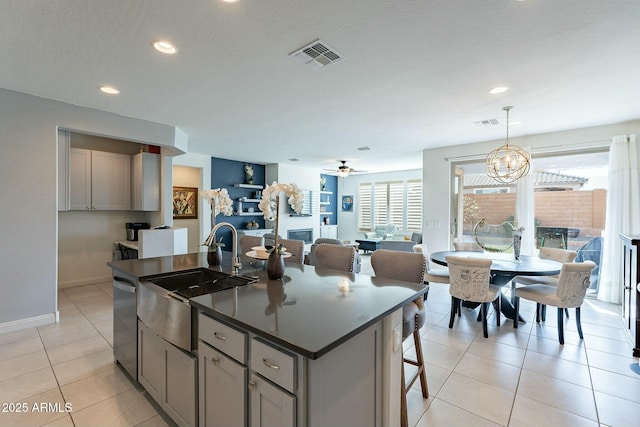 kitchen featuring sink, light tile patterned floors, gray cabinets, dishwasher, and a kitchen island with sink