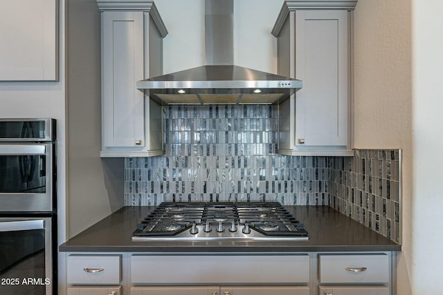 kitchen with stainless steel appliances, tasteful backsplash, gray cabinets, and wall chimney exhaust hood