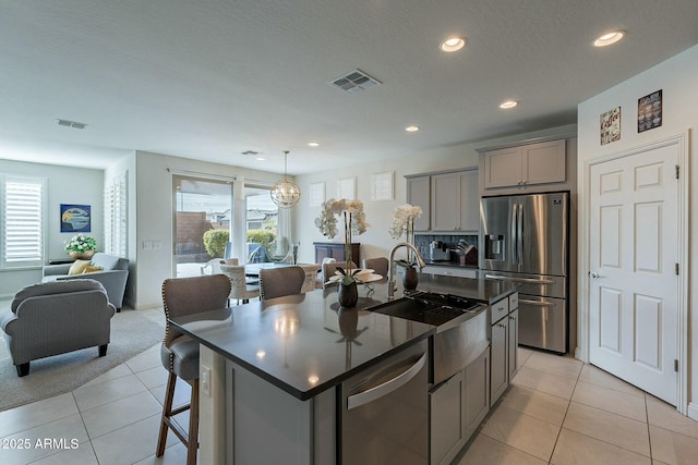 kitchen with gray cabinets, an island with sink, appliances with stainless steel finishes, and sink