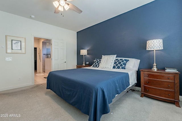 bedroom featuring ensuite bathroom, light colored carpet, and ceiling fan