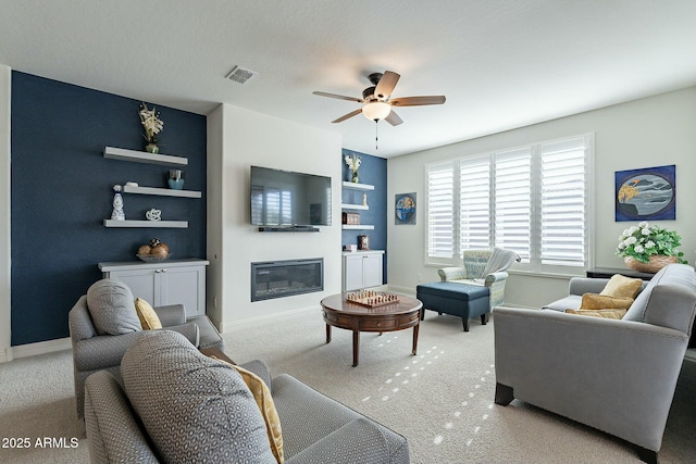 carpeted living room with built in shelves and ceiling fan