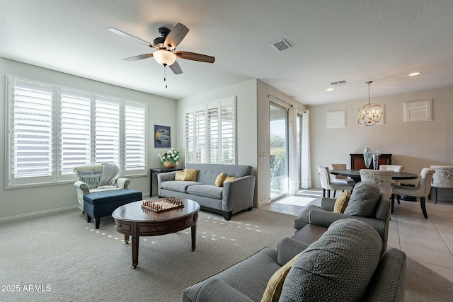 living room featuring light tile patterned floors, ceiling fan with notable chandelier, and a wealth of natural light