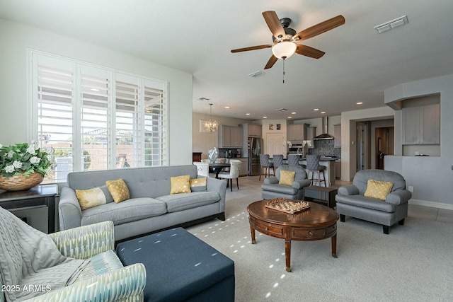 carpeted living room featuring ceiling fan with notable chandelier