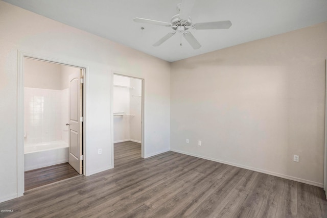 unfurnished bedroom with ensuite bathroom, a walk in closet, dark hardwood / wood-style flooring, a closet, and ceiling fan