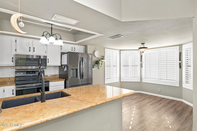 kitchen with appliances with stainless steel finishes, light stone countertops, white cabinets, dark hardwood / wood-style flooring, and decorative light fixtures