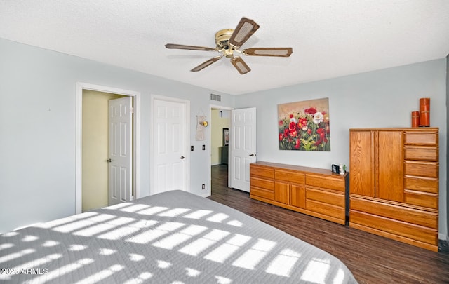 bedroom featuring ceiling fan, dark hardwood / wood-style floors, and a textured ceiling