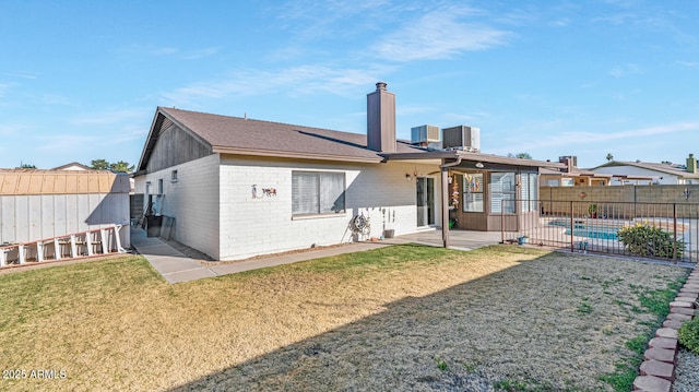 back of property with cooling unit, a fenced in pool, a patio area, and a lawn