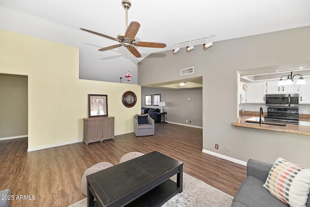 living room featuring high vaulted ceiling, dark hardwood / wood-style floors, track lighting, and ceiling fan