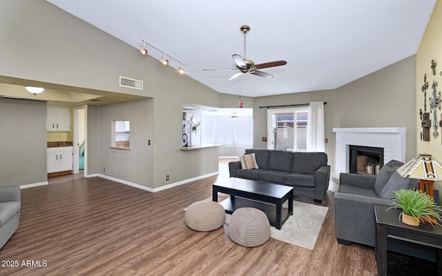 living room with ceiling fan, lofted ceiling, dark hardwood / wood-style floors, and a fireplace