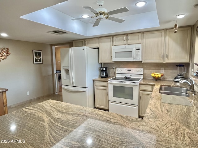 kitchen featuring a raised ceiling, decorative backsplash, sink, and white appliances