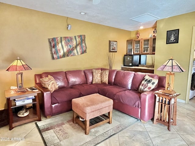 tiled living room with washer / dryer, a skylight, and a textured ceiling