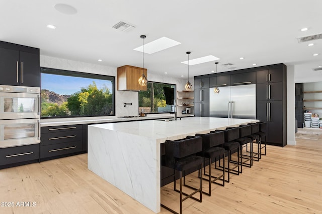 kitchen featuring visible vents, light wood-style flooring, appliances with stainless steel finishes, and backsplash