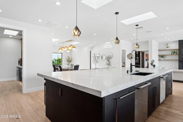 kitchen featuring pendant lighting, light wood-style floors, a large island, a sink, and a skylight
