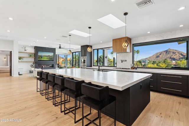 kitchen with a sink, light wood-style floors, stainless steel appliances, a large island, and visible vents
