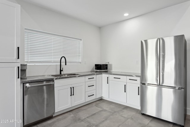 kitchen with dark countertops, a sink, stainless steel appliances, recessed lighting, and white cabinetry