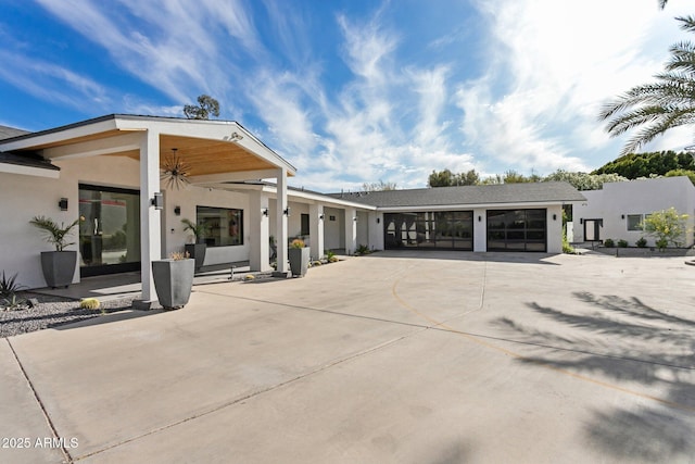 rear view of property with stucco siding and concrete driveway