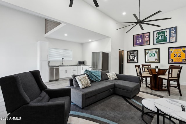 living area featuring a ceiling fan, a high ceiling, and recessed lighting